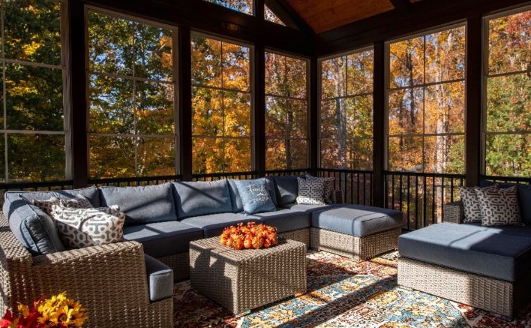 A sunroom in fall with a blue-cushioned grey sofa set and a centertable